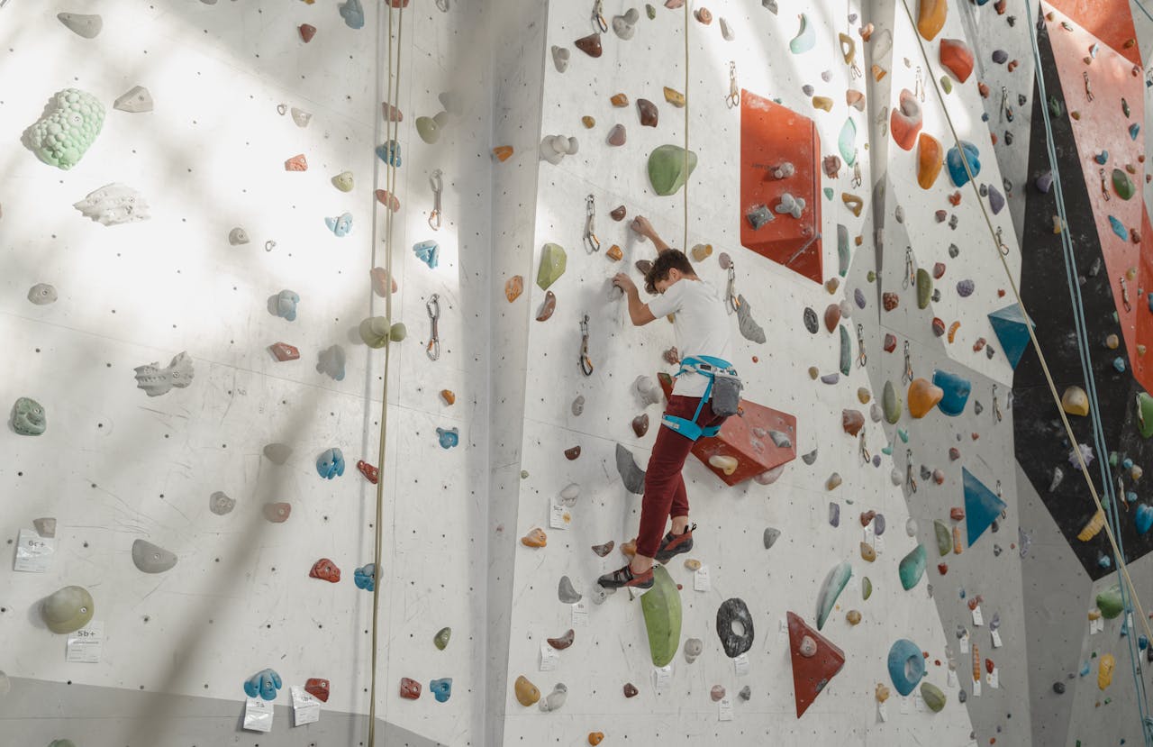 室内クライミングで壁を登る男性
